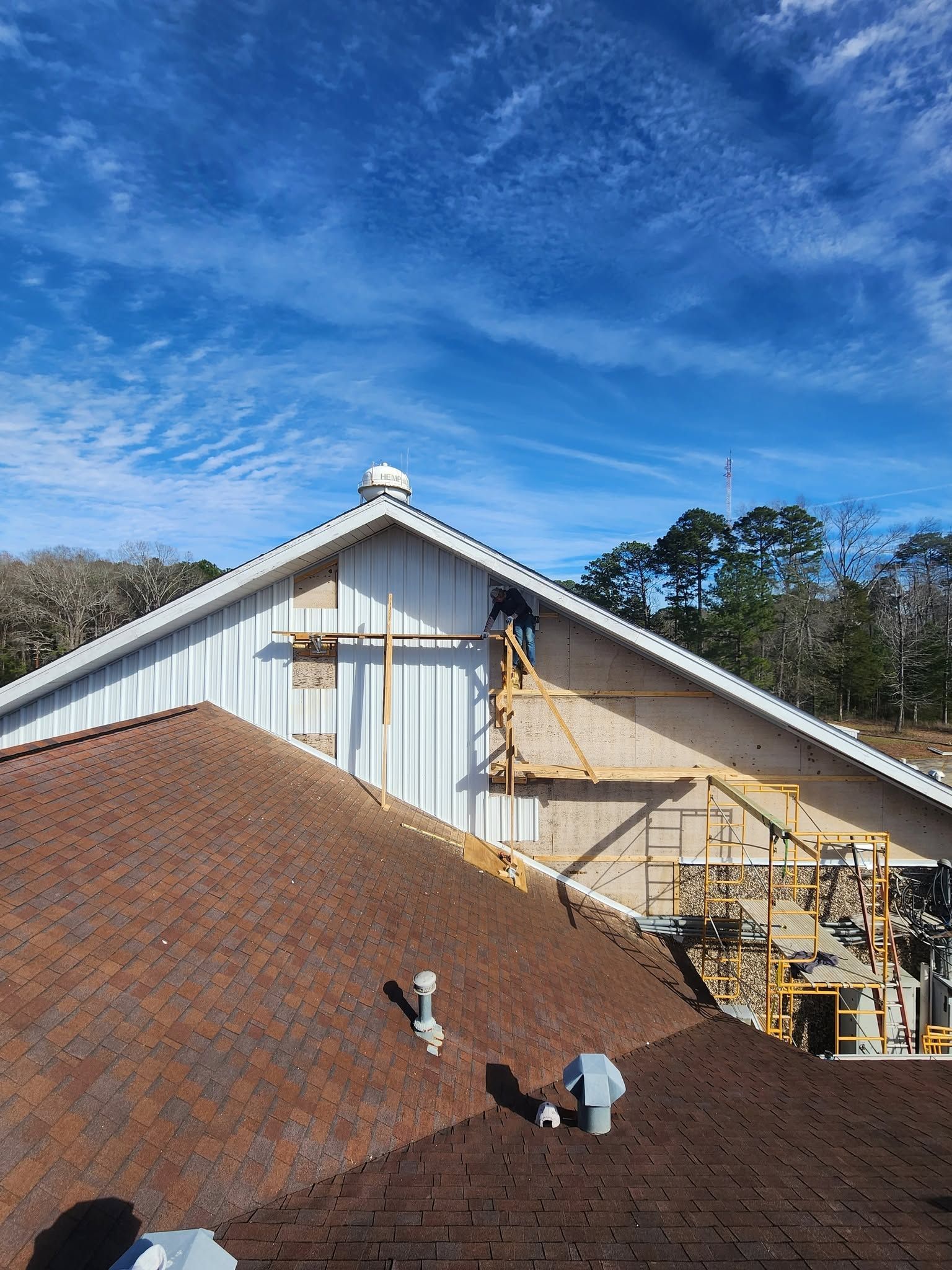Roof under construction on a house with scaffolding, against a blue sky