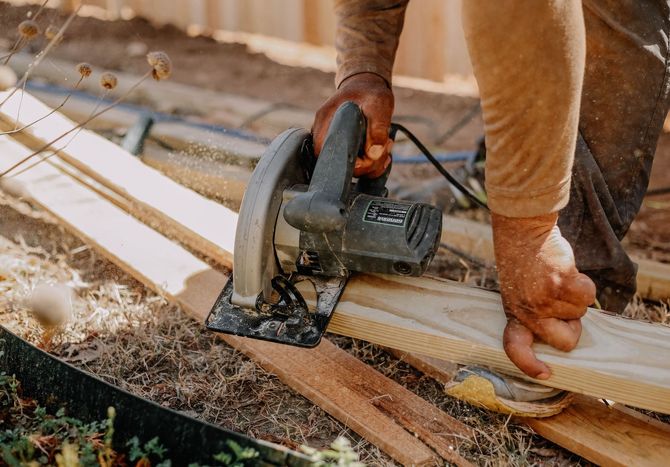 Person using a circular saw to cut a wooden board on a construction site
