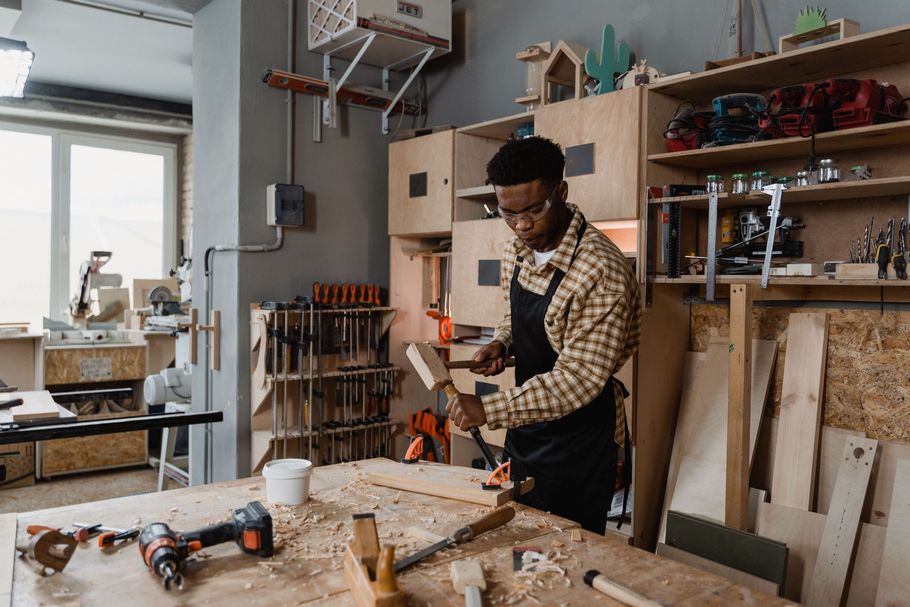 Person working with tools at a woodworking bench in a bright workshop