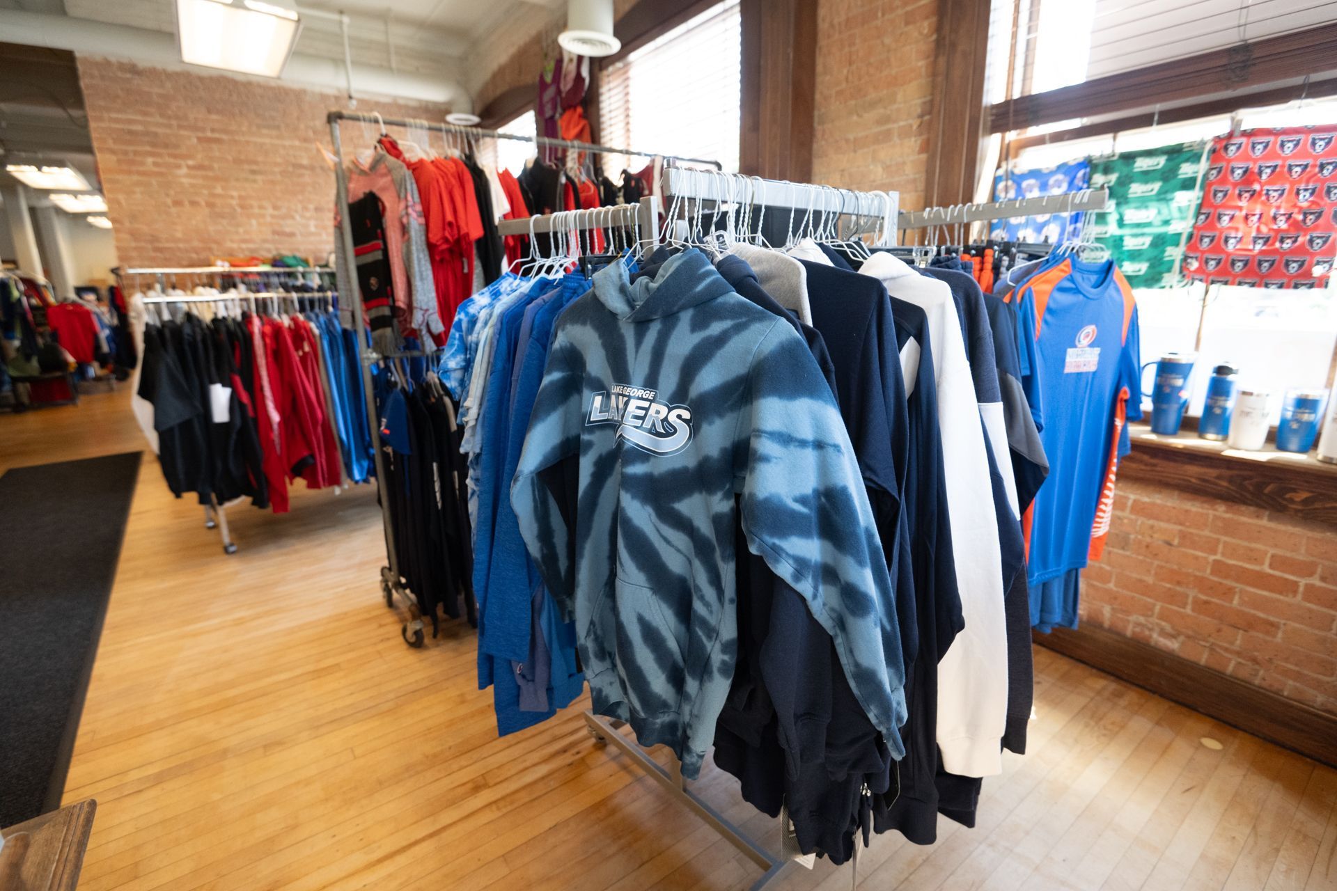 A tie dye sweatshirt is hanging on a rack in a store.