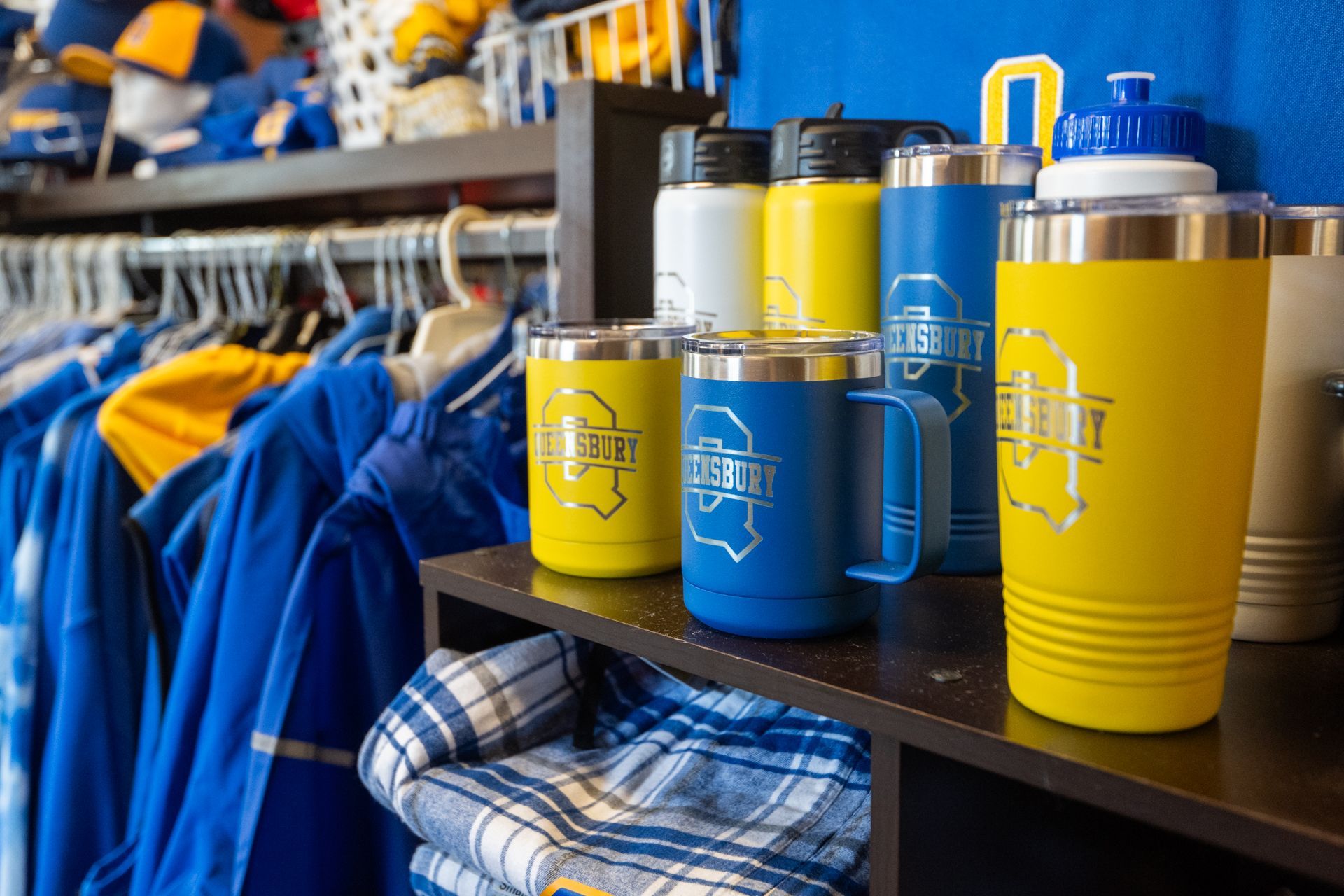 A shelf filled with a variety of mugs and water bottles in a store.