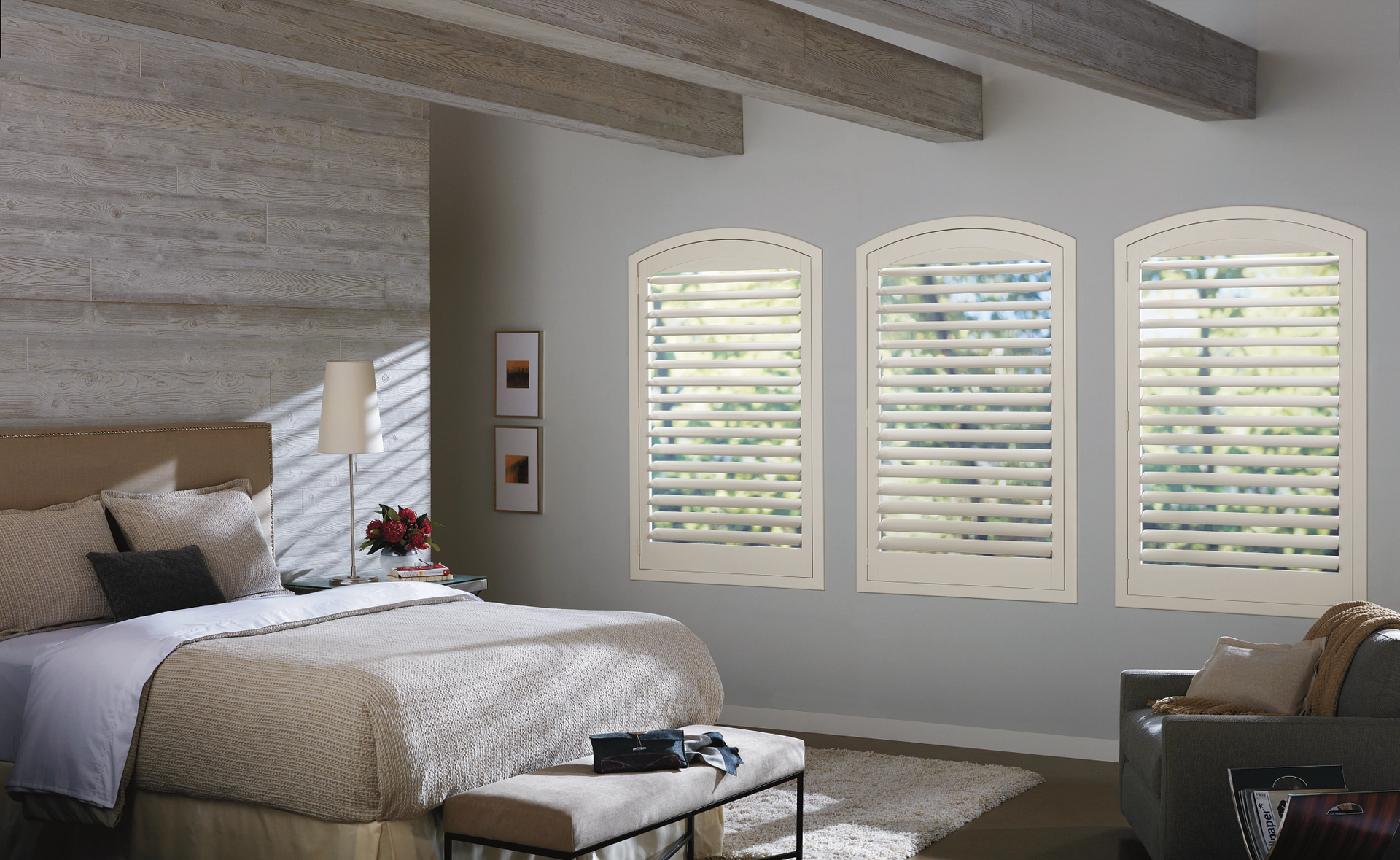 A bedroom with a bed and three windows with shutters
