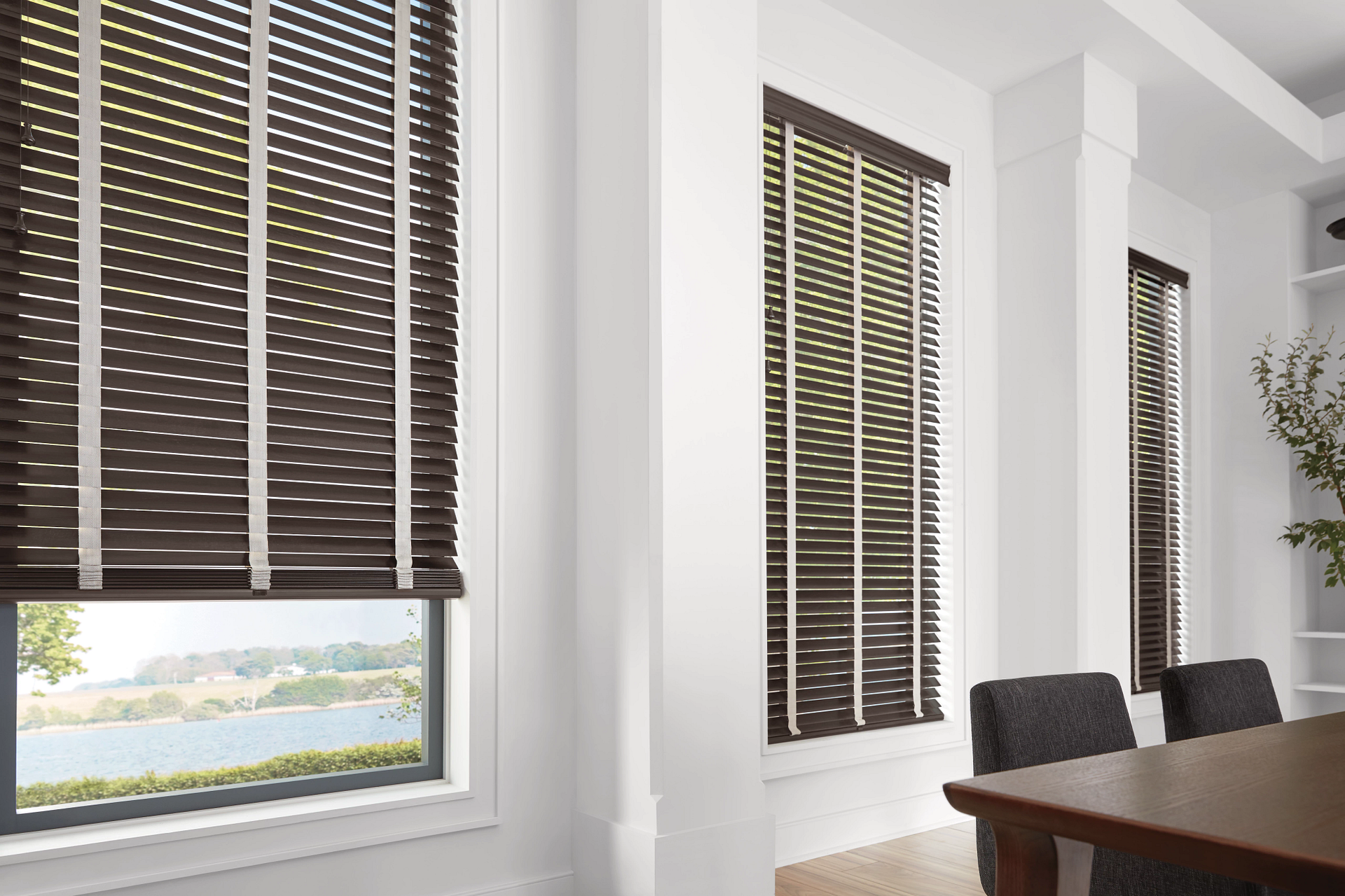 A dining room with a table and chairs and wooden blinds on the windows.