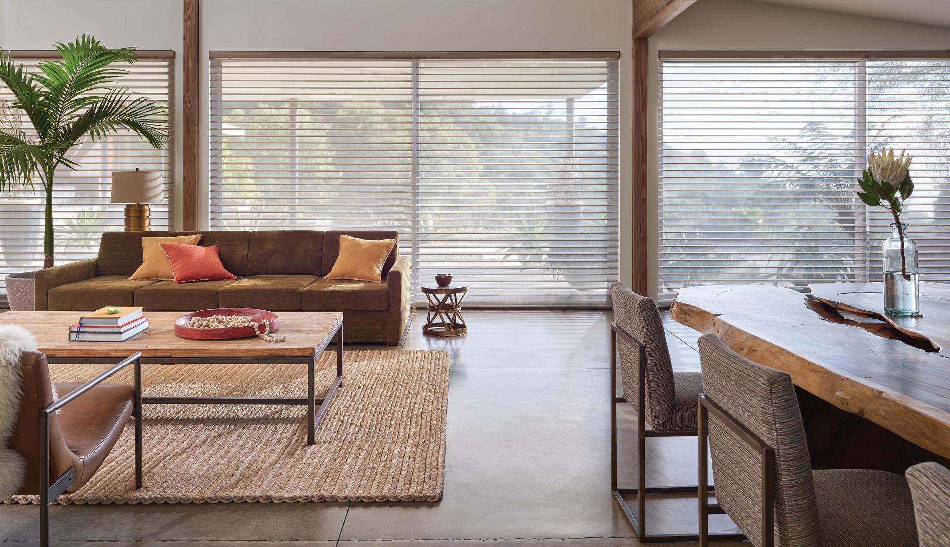 A living room with a couch , table , chairs and a large window.