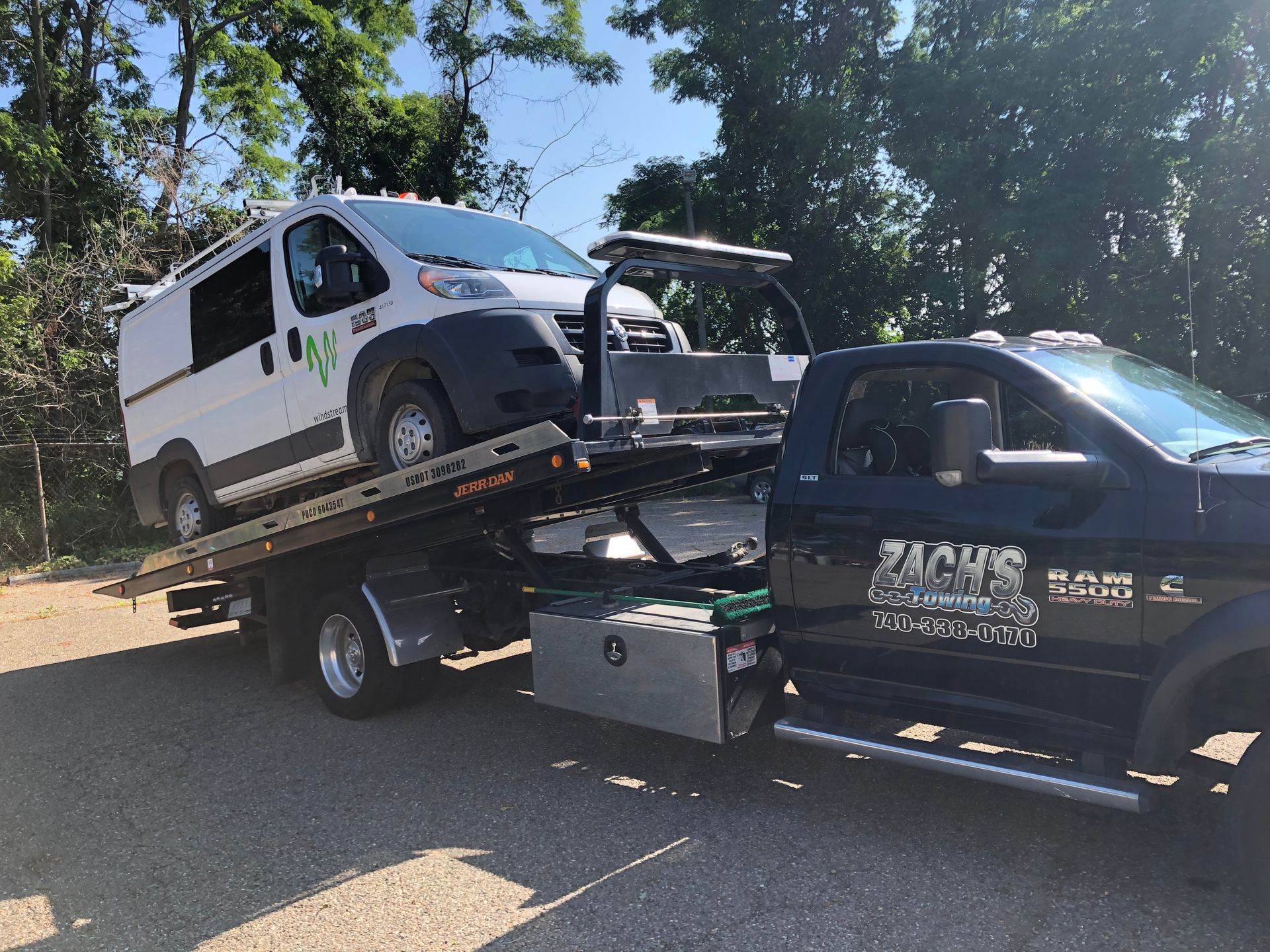 A white van is being towed by a tow truck.