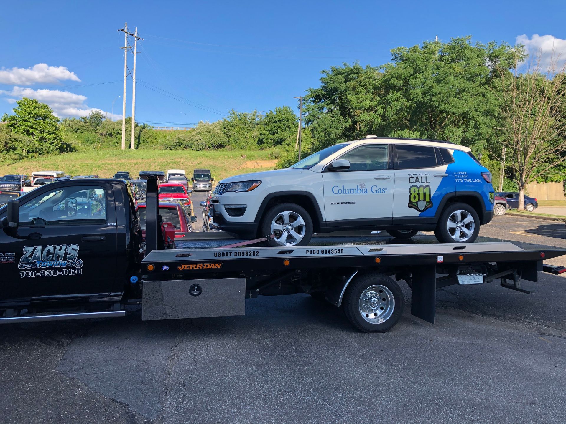 A jeep is being towed by a tow truck in a parking lot.