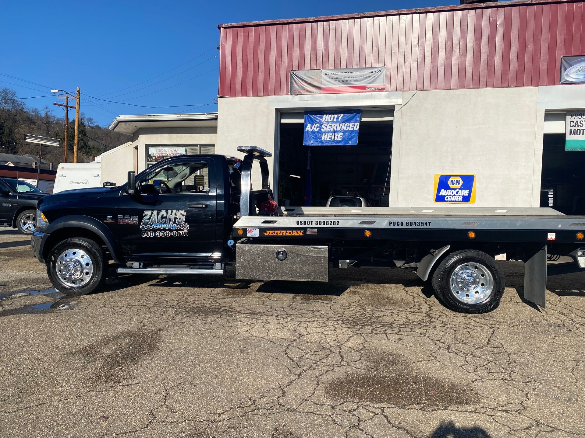 A black tow truck is parked in front of a building.