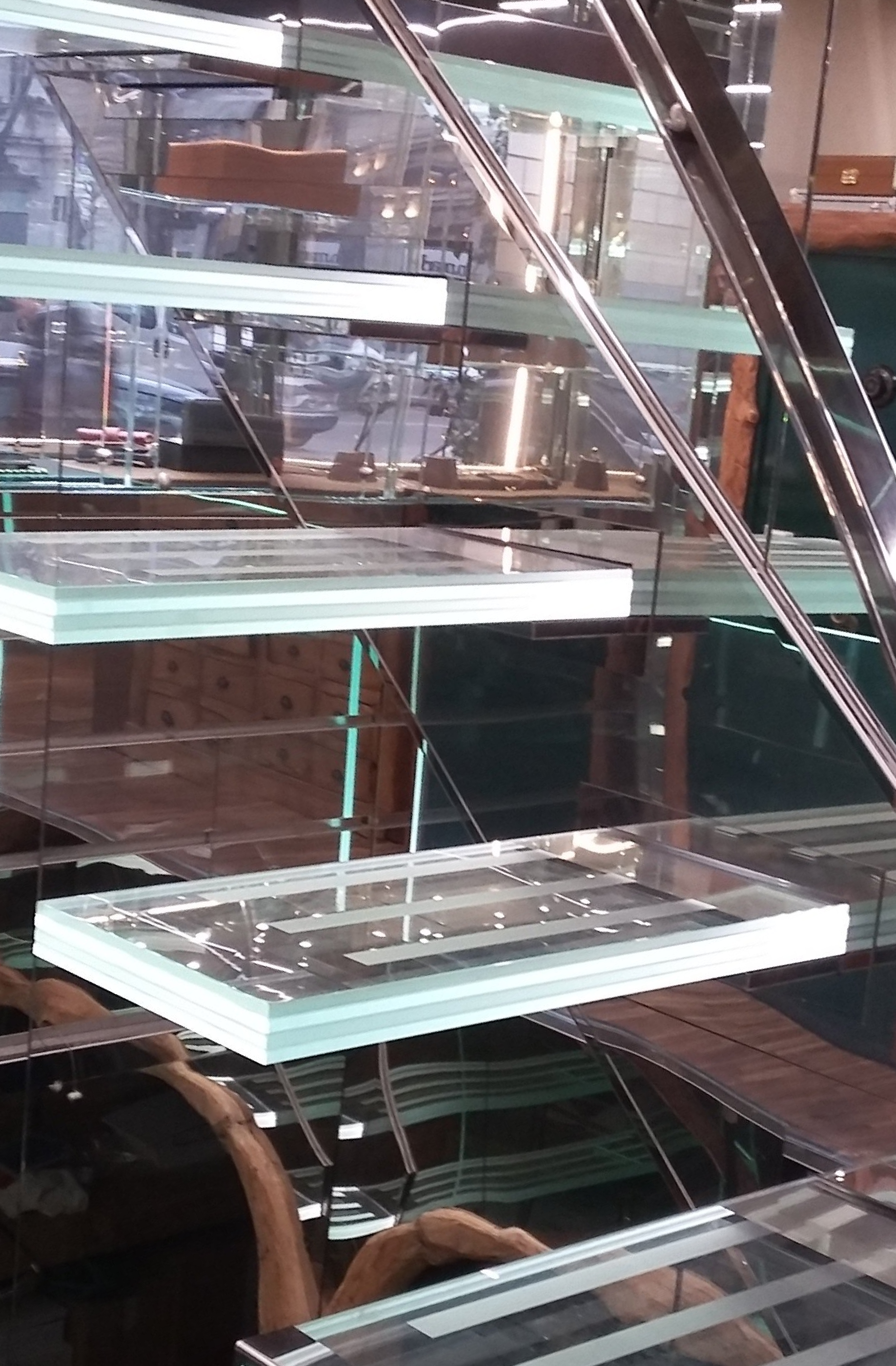 Scala in vetro con supporti metallici e luce riflessa.