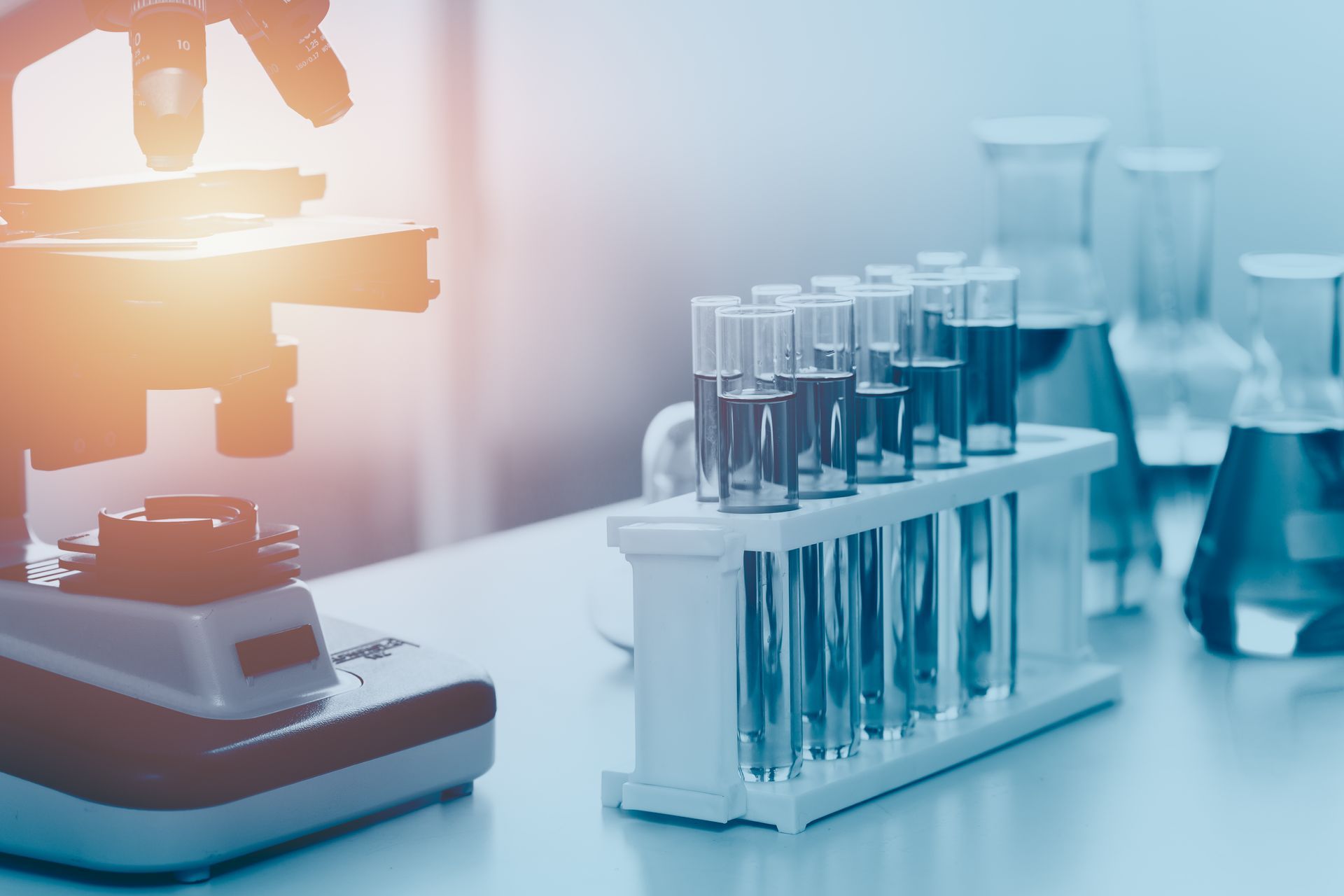 Microscope beside test tubes and lab glassware in a bright medical research lab