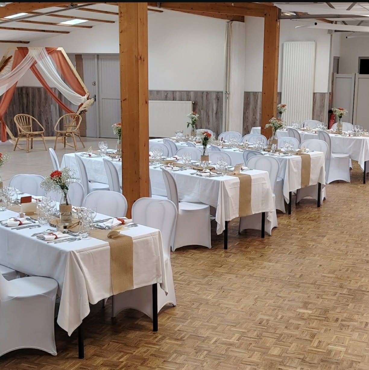 Salle de banquet avec tables et chaises nappées de blanc, dressées pour un événement