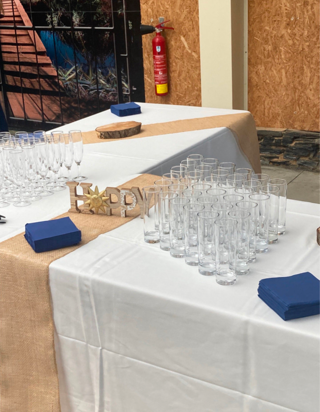 Table blanche avec des rangées de verres transparents, des serviettes bleues et une décoration « LOVE ».