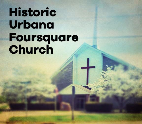 Historic Urbana Foursquare Church building with a cross on the front, surrounded by trees.