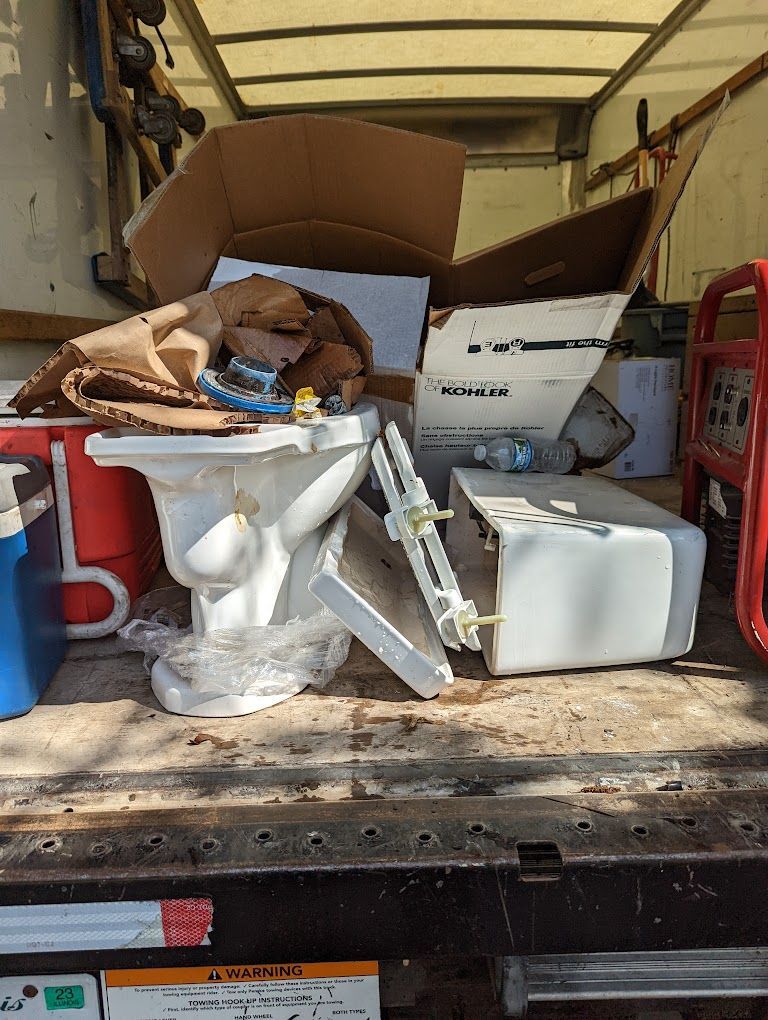 A white toilet is sitting on the back of a truck.