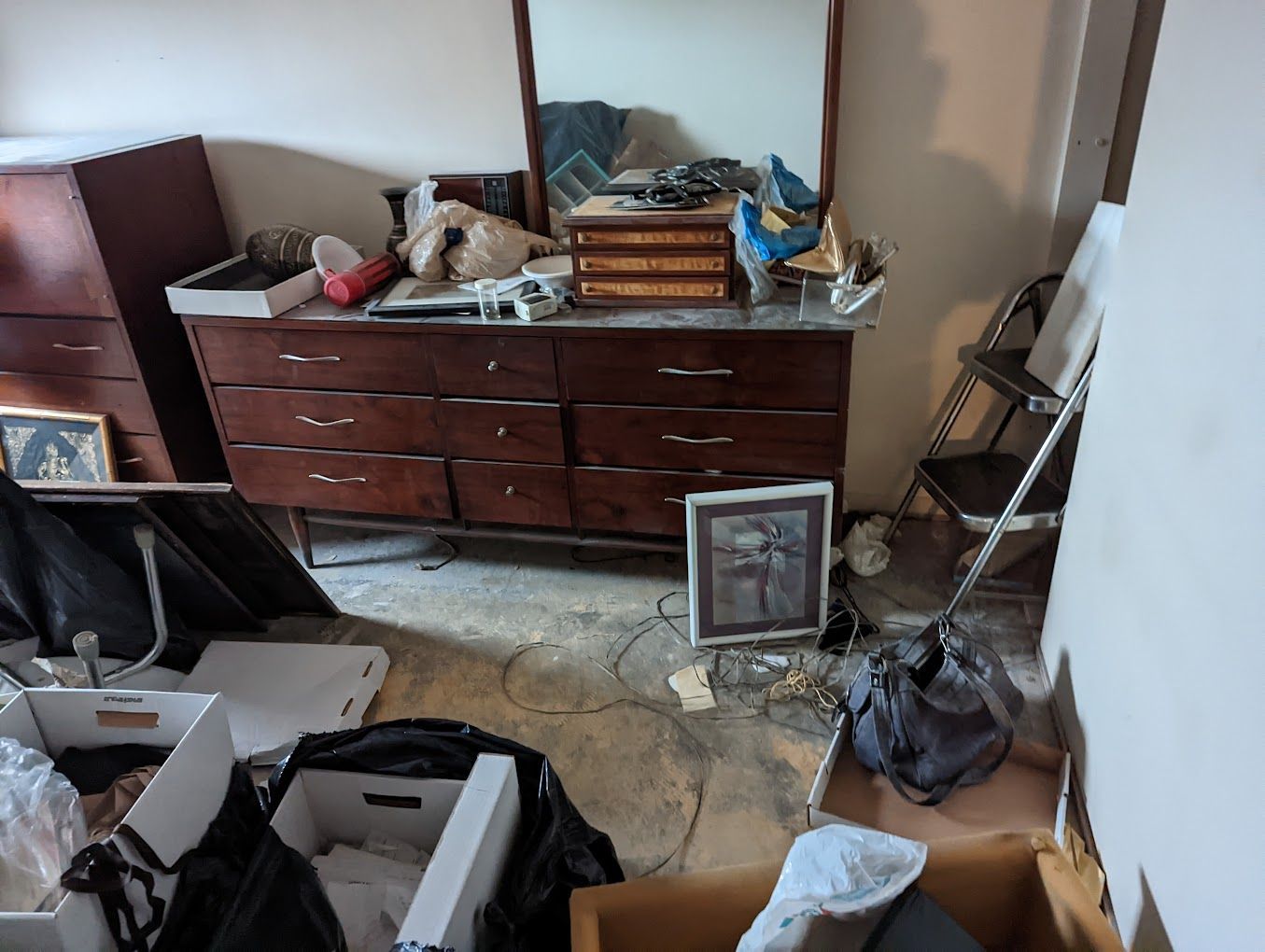 A messy room with a dresser and a mirror