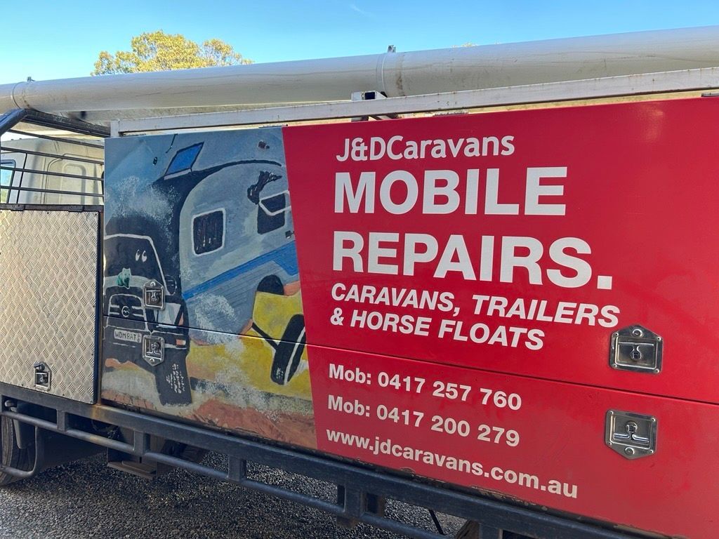 Red J&D Caravans mobile repairs sign on a trailer, with contact numbers and caravan images — J & D Caravans In Tamaree, QLD