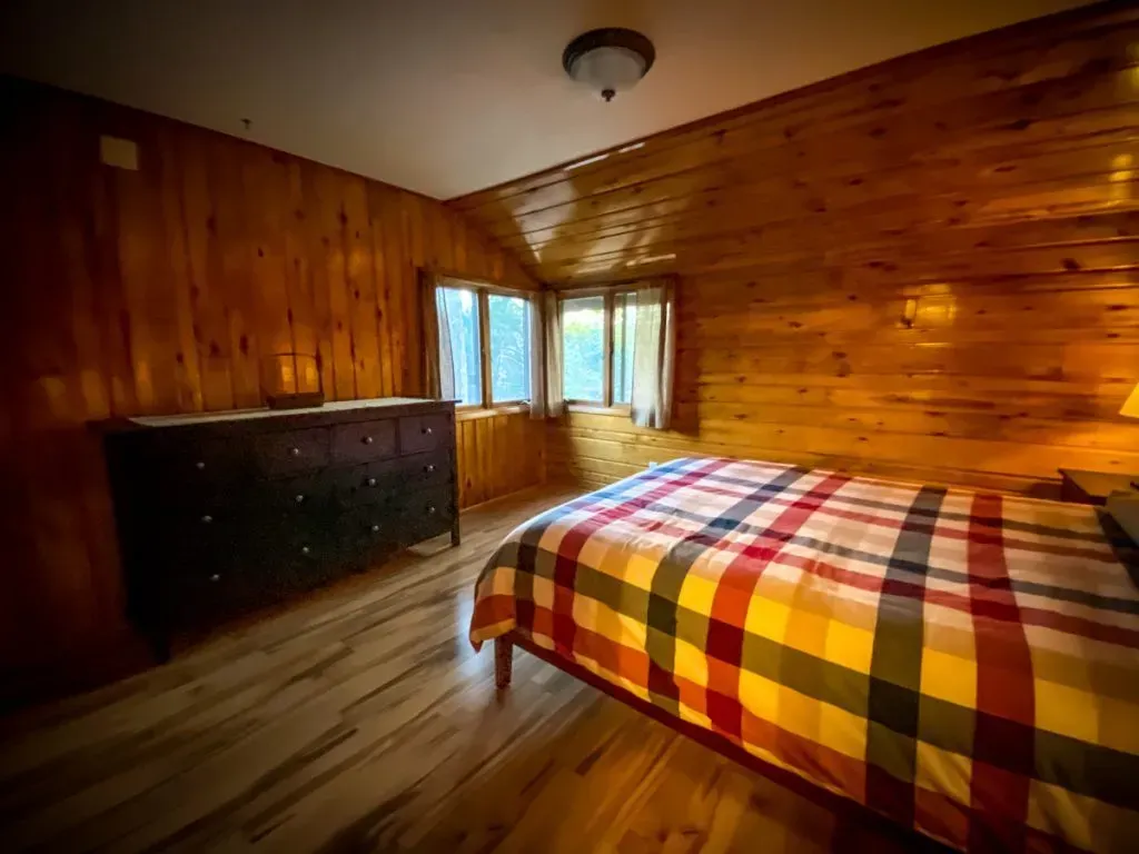 A bedroom with a bed , dresser , and window.