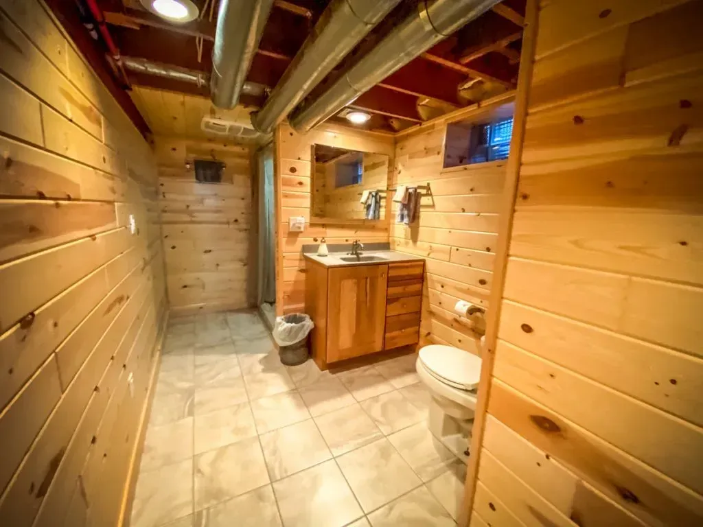 A bathroom in a log cabin with a toilet , sink and mirror.