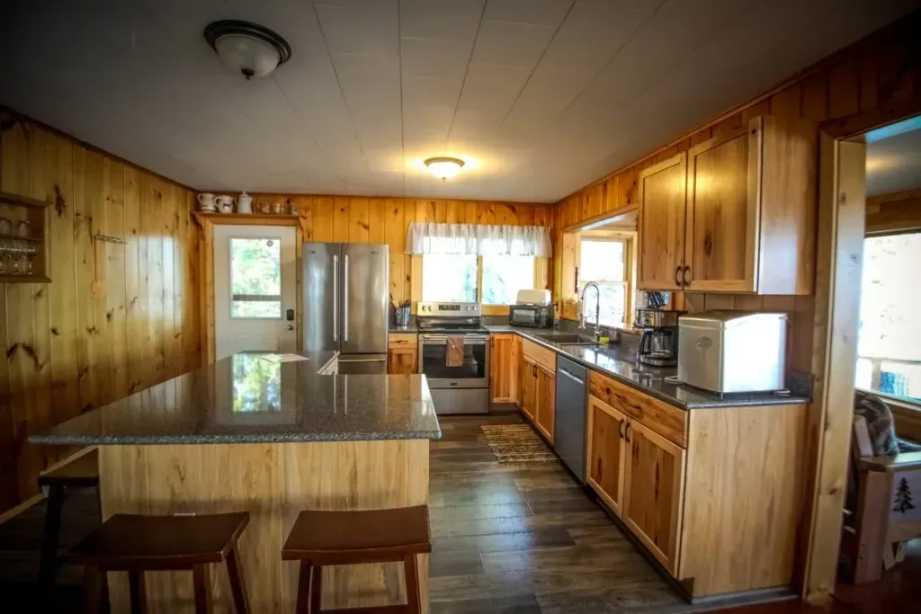A kitchen with wooden cabinets , granite counter tops , and stools.