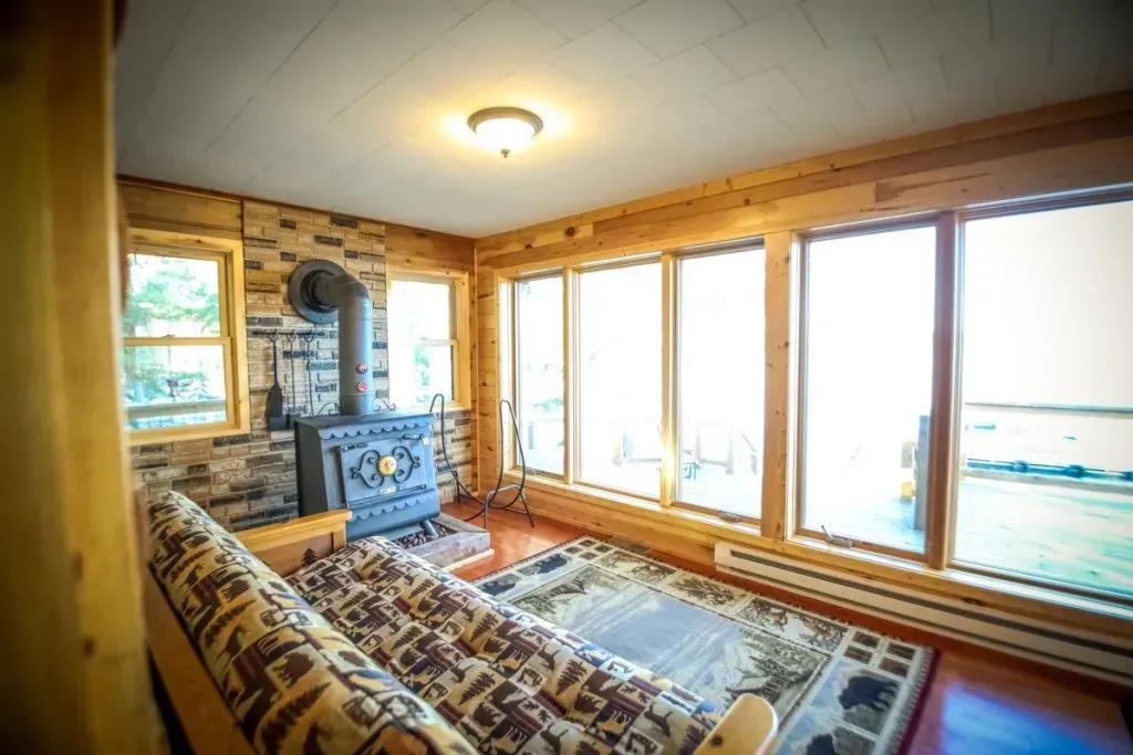 A living room with a couch , fireplace , and lots of windows.