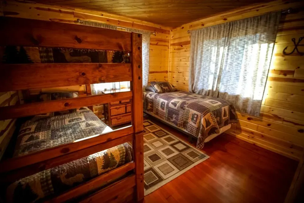 A bedroom in a log cabin with bunk beds and two beds.