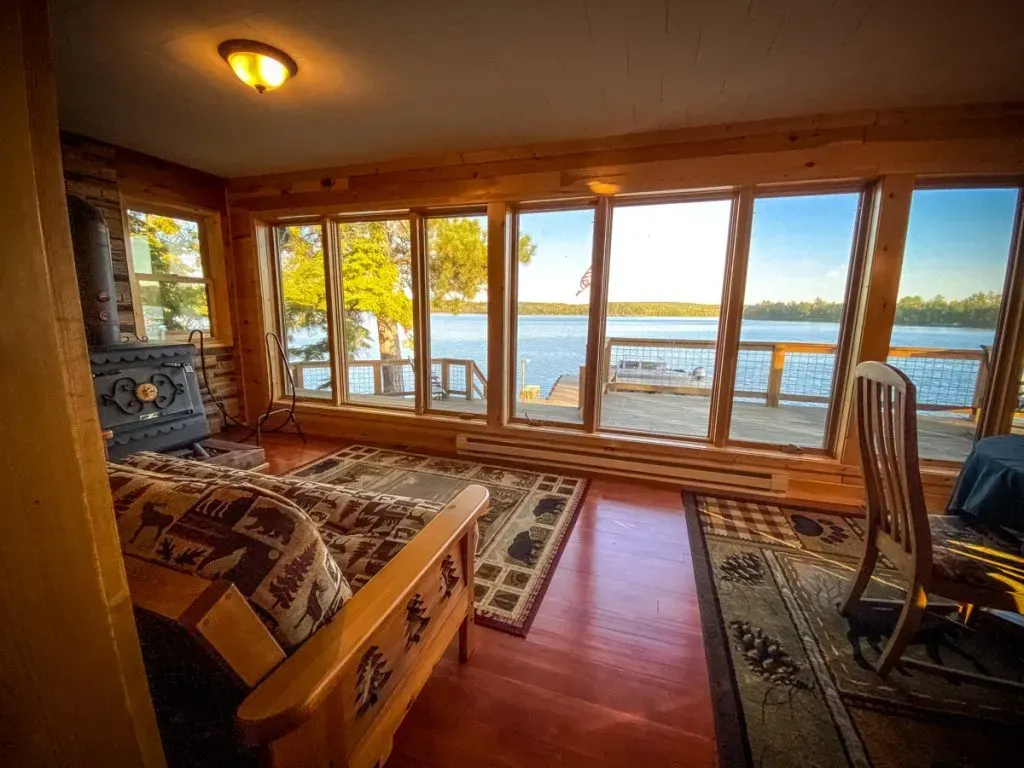 A living room with a lot of windows overlooking a lake.