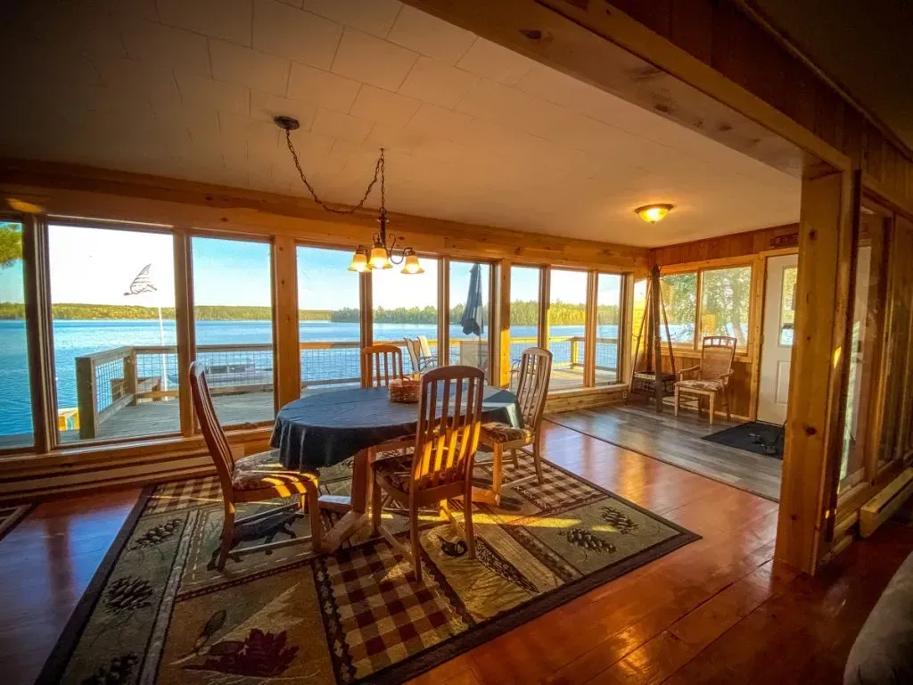 A dining room with a table and chairs and a view of a lake.