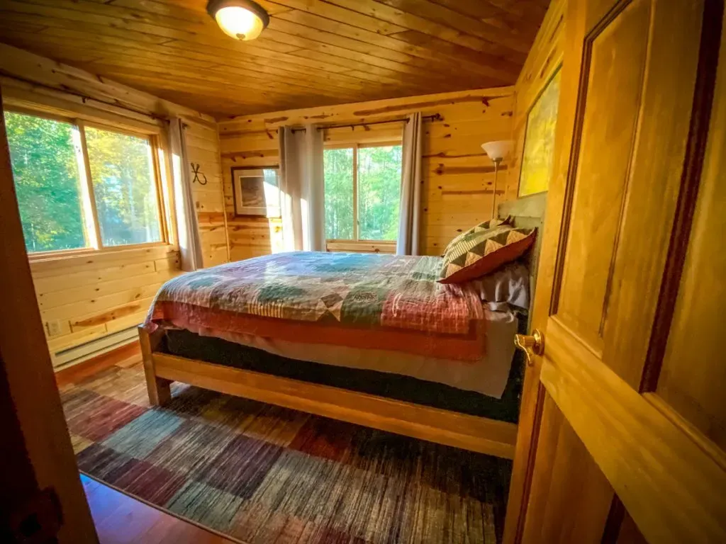 A bedroom in a log cabin with a king size bed and a rug.
