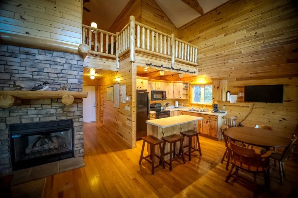 A large wooden cabin with a kitchen , dining room , and fireplace.