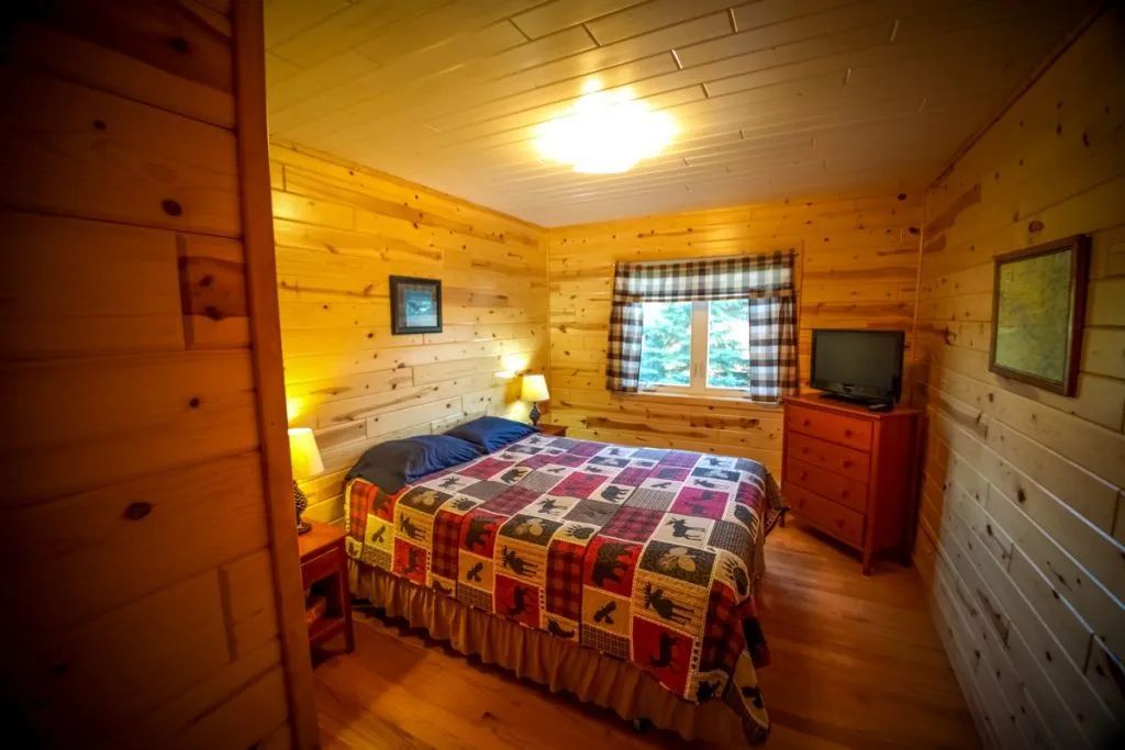 A bedroom in a log cabin with a king size bed and a television.