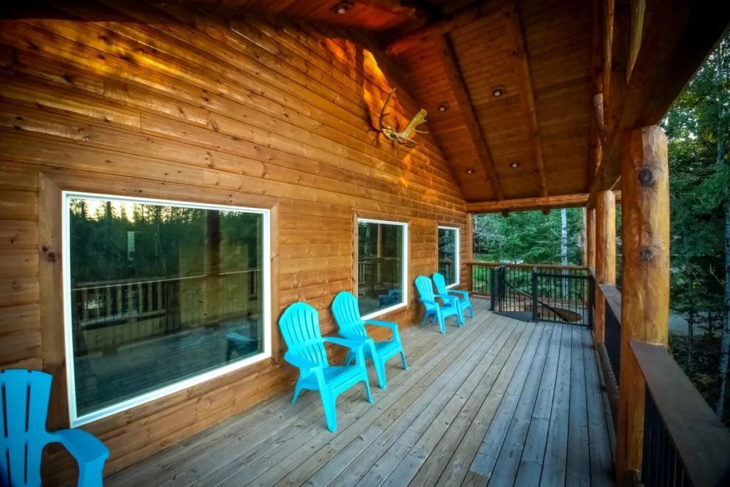 A wooden deck with blue chairs and a ceiling fan.