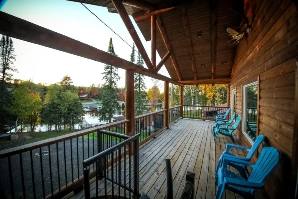 A wooden deck with blue chairs and a view of a lake