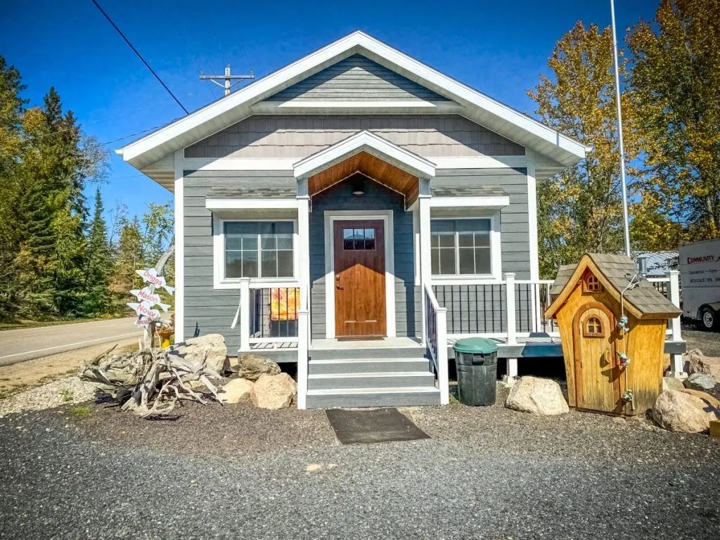 A small house with a wooden door and stairs is for sale.