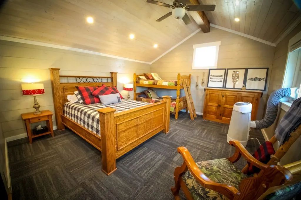 A bedroom with a bed , chairs , nightstands , and a ceiling fan.
