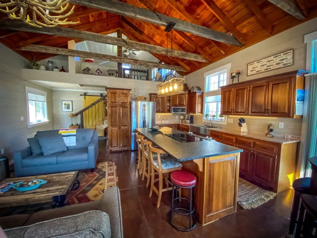A living room and kitchen in a house with a wooden ceiling.