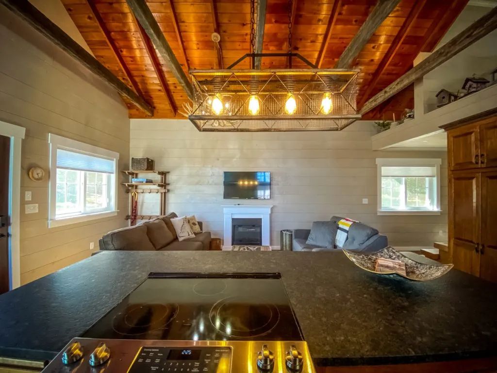 A kitchen with a stove top oven and a living room in the background.