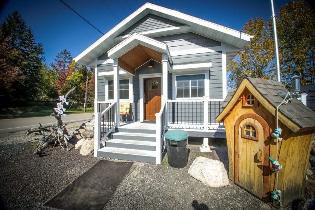 A small house with a wooden playhouse in front of it