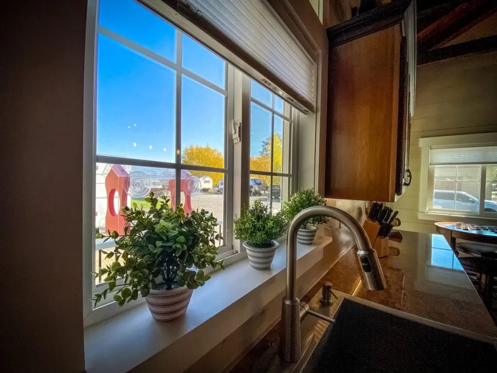 A kitchen with a sink and a window with potted plants on the window sill.