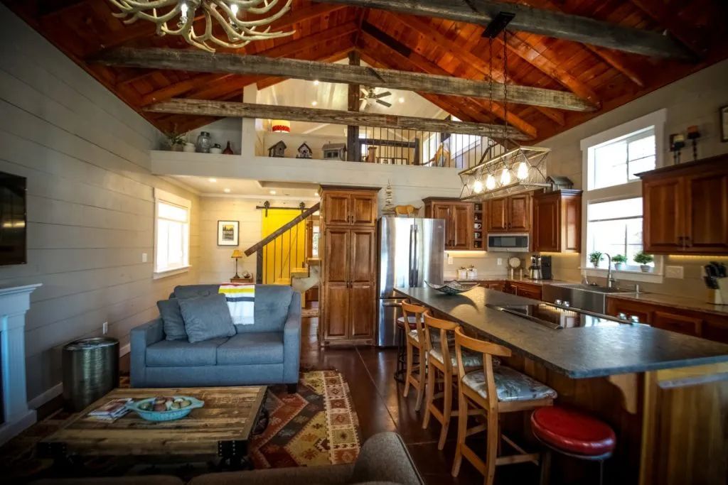 A living room with a couch , table , chairs and a kitchen.