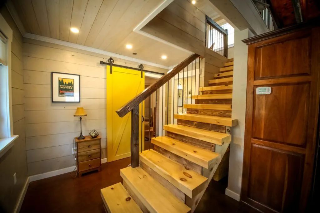 A wooden staircase in a house with a yellow sliding barn door.