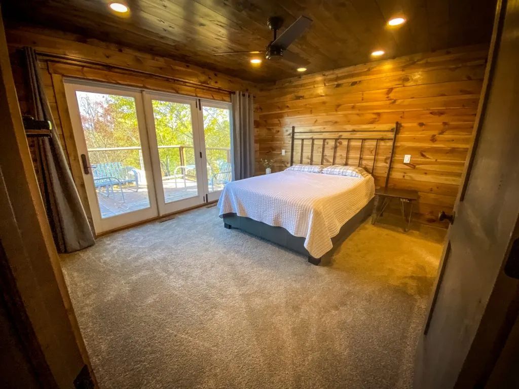 A bedroom in a log cabin with a king size bed and sliding glass doors.