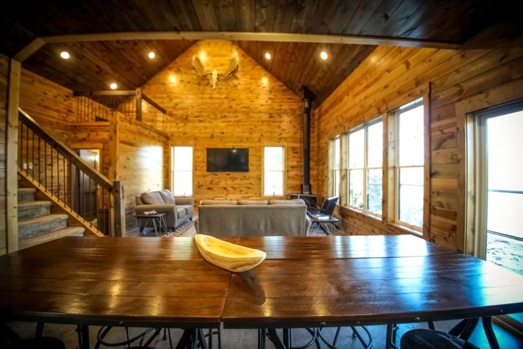 A large wooden table in a log cabin with a bowl on it.