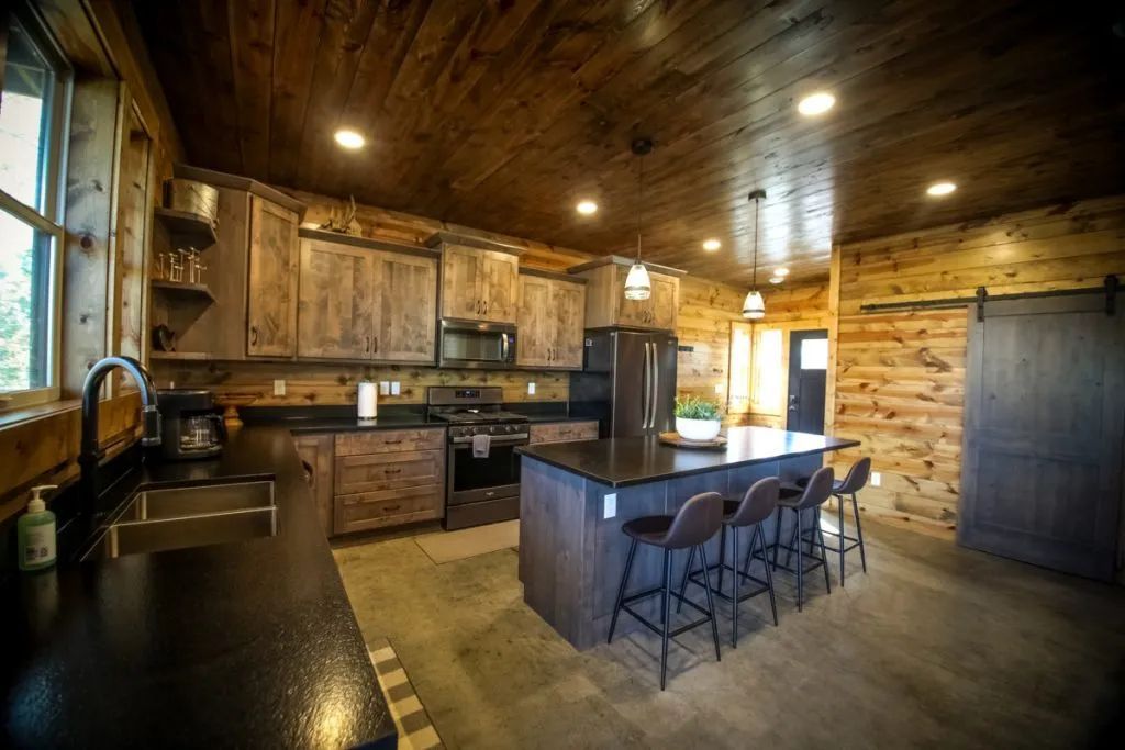 A kitchen in a log cabin with a large island and stools.