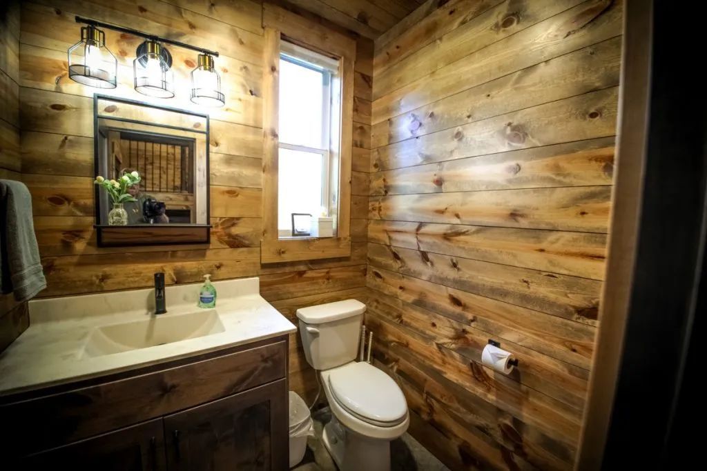 A bathroom in a log cabin with a toilet , sink and mirror.