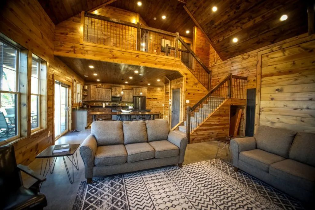 A living room filled with furniture and a staircase in a log cabin.