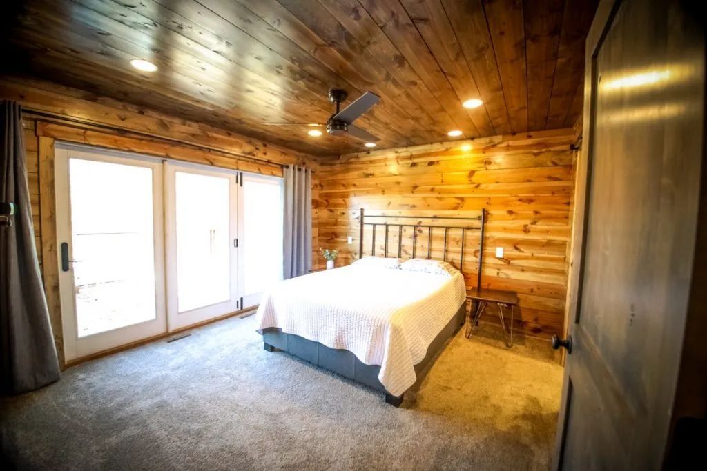 A bedroom in a log cabin with a large bed and sliding glass doors.