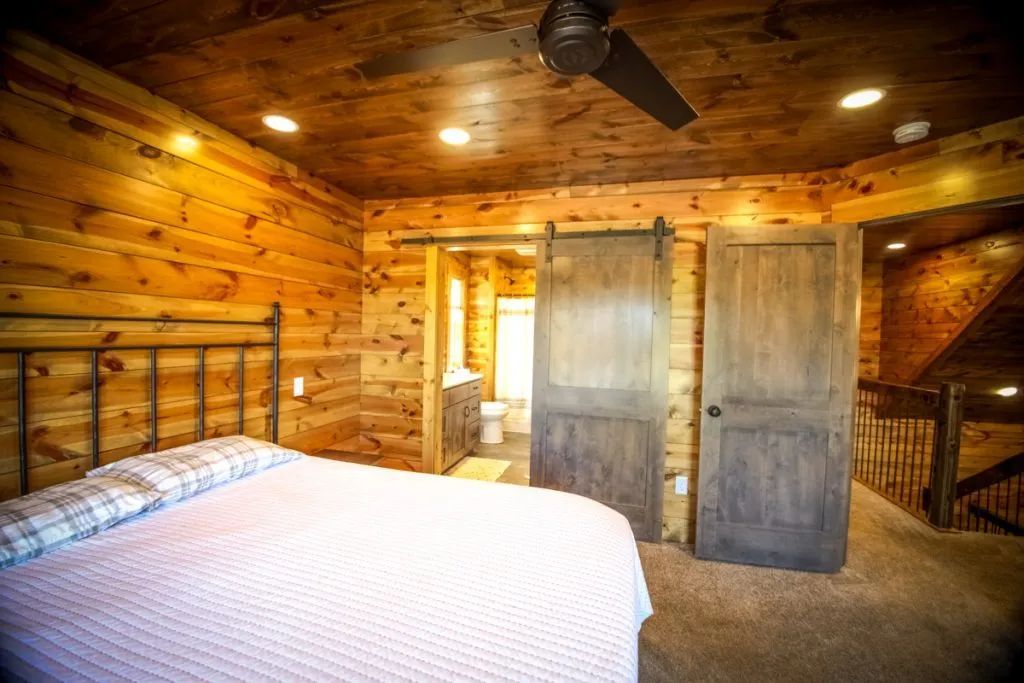 A bedroom in a log cabin with a king size bed and sliding barn doors.