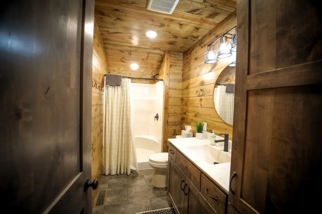 A bathroom with a sink , toilet , shower and mirror.