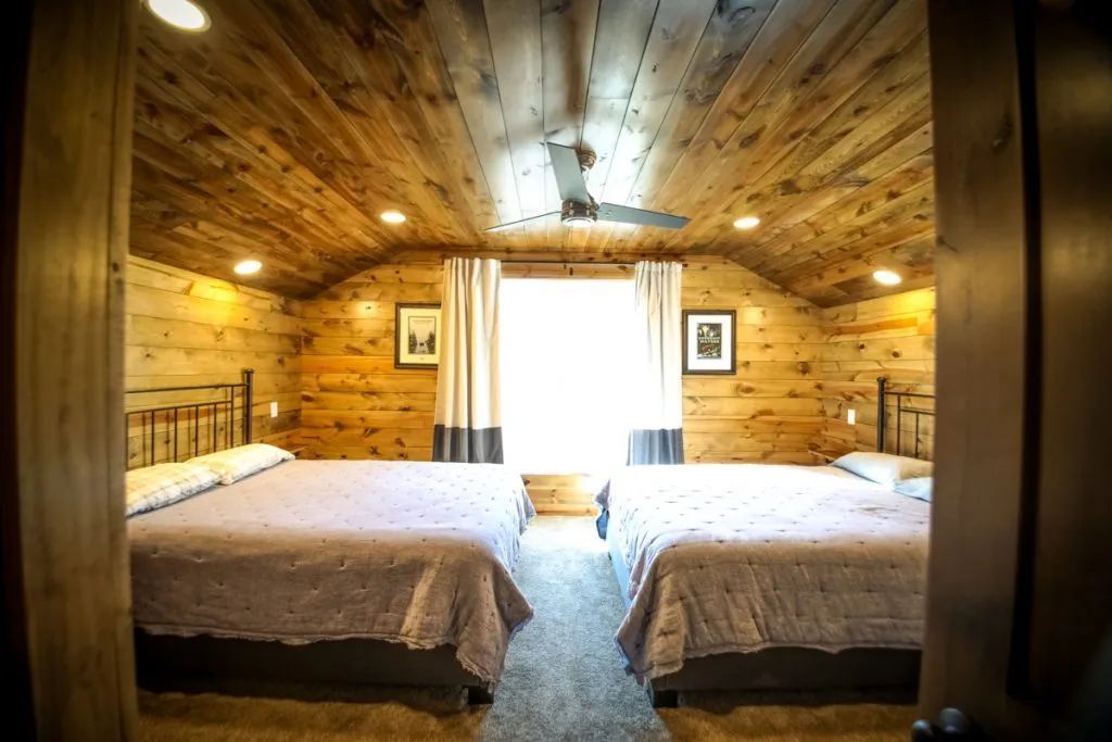 A bedroom with two beds and a ceiling fan.