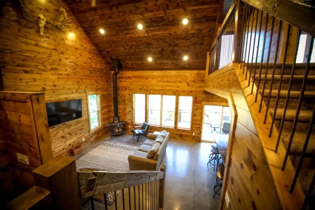 A living room in a log cabin with stairs leading up to the second floor.