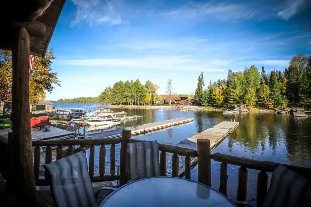 A table and chairs on a porch overlooking a lake.